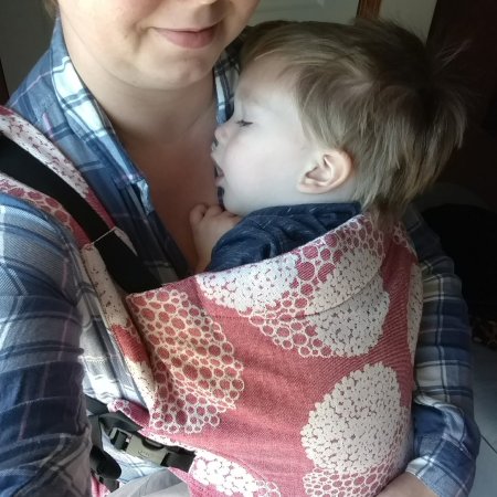 Selfie of a woman carrying a sleeping toddler in a pink floral print carrier